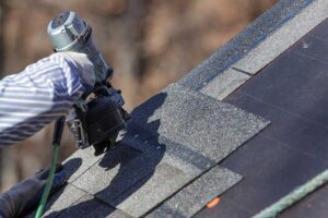 Metal roof flashing protects a chimney and vent pipe on a shingled residential roof after rain.